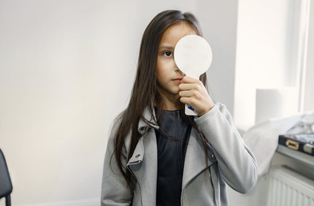 A girl doing an eye examination, she's covering her left eye while looking at far to test he visual acuity.