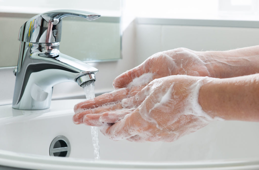 A close-up of a person's hand being washed by soap and water.