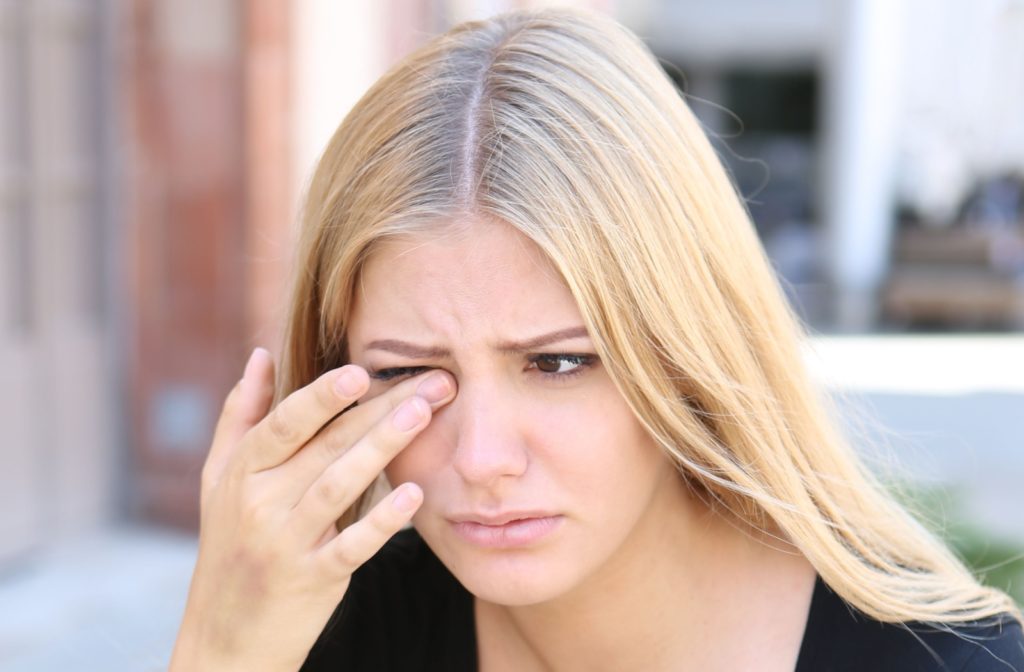 A woman experiencing discomfort in her eye possibly caused by eye irritation.
