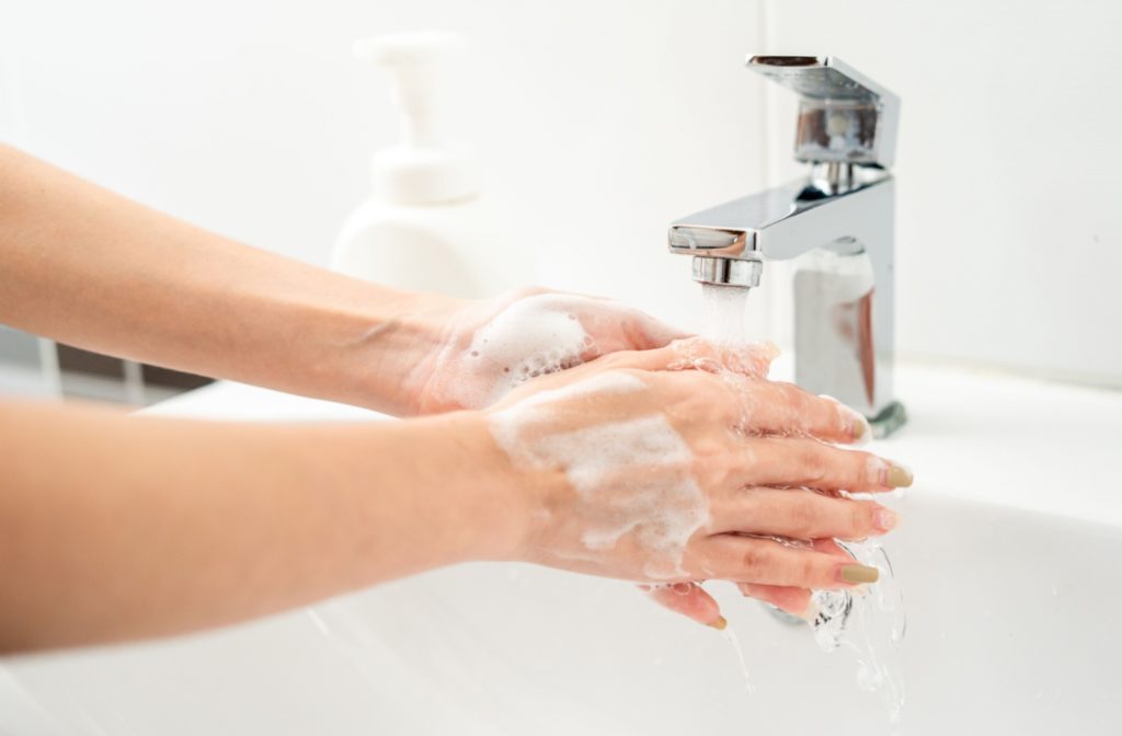 A close up of a woman washing her soap-covered hands.