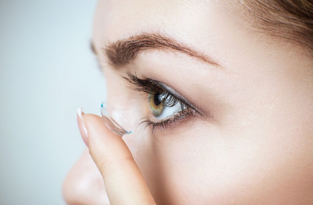 Profile of a person's face as they prepare to put their contact lens into their eye.