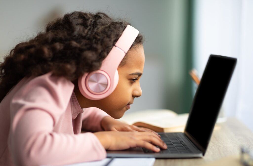 A child using a laptop for school work squints at the screen.