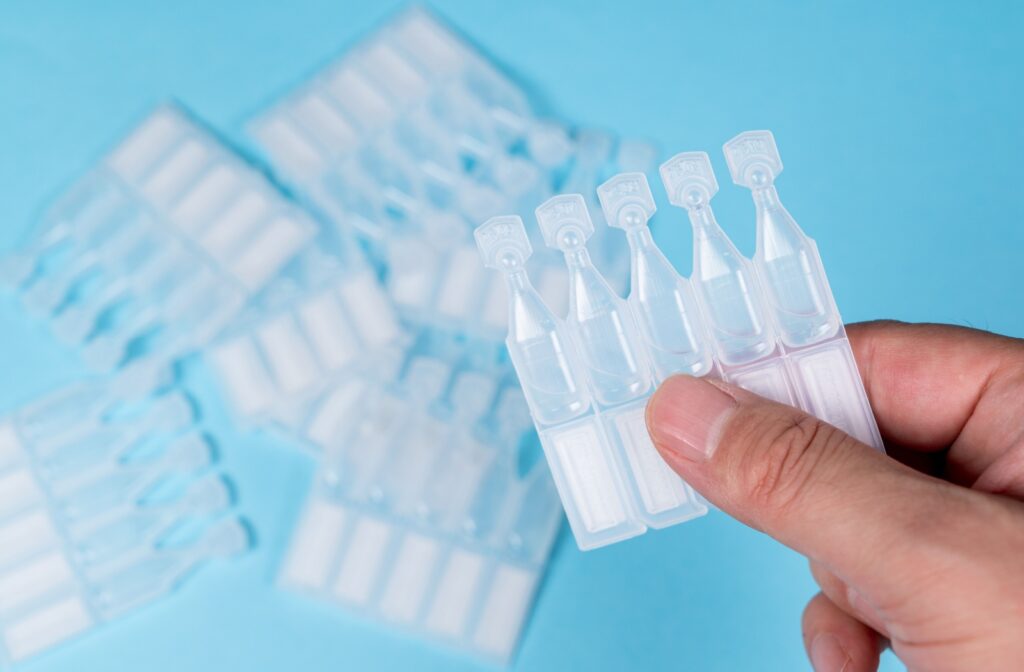 Close-up of a hand holding disposable vials of artificial tears.