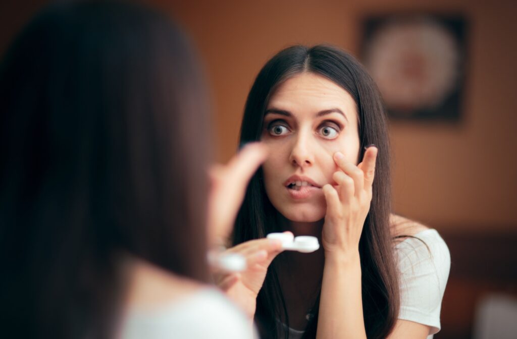 A person looking in the mirror, putting a contact lens in