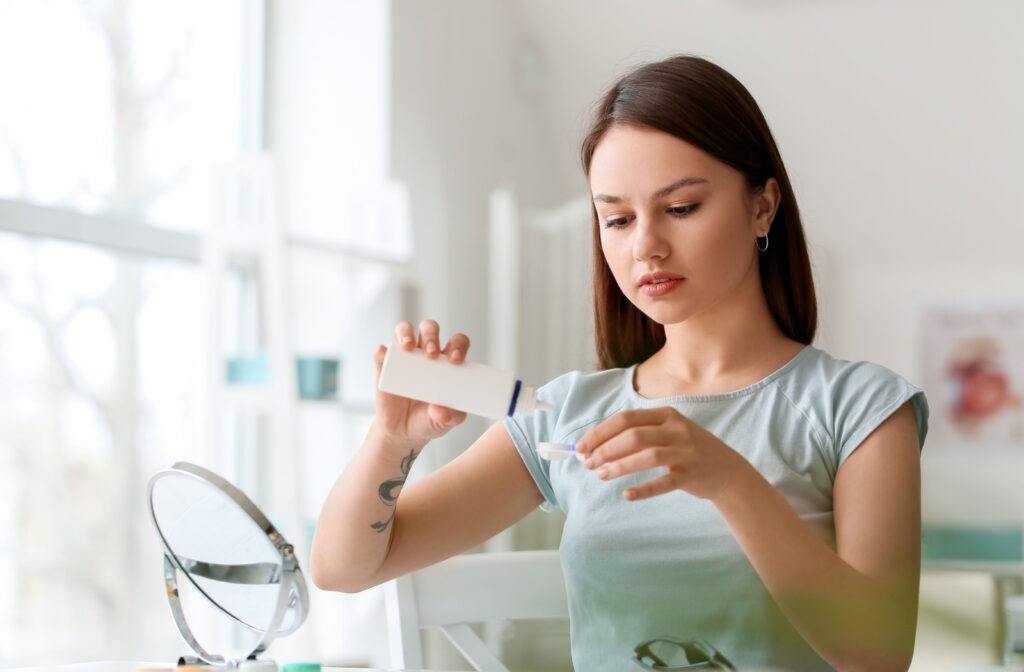 A person putting contact lens solution into their contact lens case to keep their contact lenses clean.