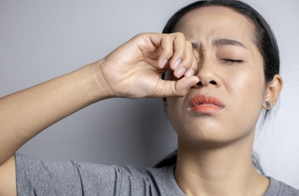 A person holding their hand up to their eye after scratching it.