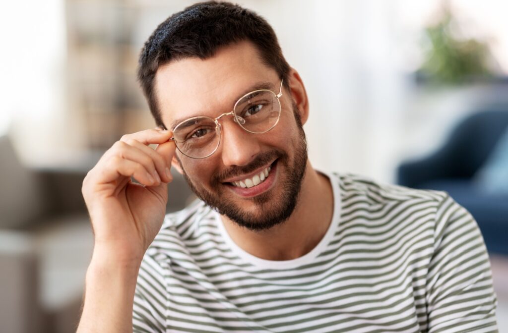 A person smiling, holding their glasses.